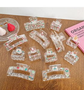 Flat lay of acrylic Christmas hair claw clips with Santa and reindeer prints on wood table