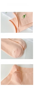 Detail of light orange cotton socks featuring floral embroidery and reinforced heel