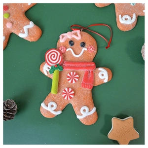 Macro detail of a gingerbread man ornament with red scarf on a festive green background