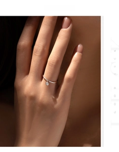 Detail of S925 sterling silver ring with a round dangling moissanite pendant on finger