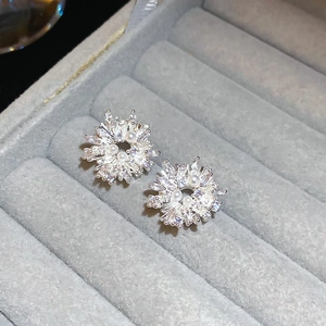 Macro detail of silver snowflake stud earrings with sparkling zircons and a central pearl