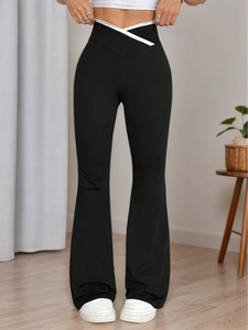 High-waisted black flared trousers with white V-shaped patchwork and elastic knit fabric