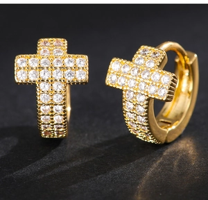 Macro view of gold-plated cross huggie earrings with sparkling white cubic zirconia