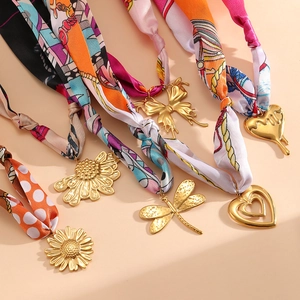 Dettaglio di ciondoli placcati oro 18K su collane a foulard in seta con fantasie varie