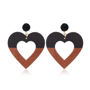 Detail view of heart-shaped drop earrings with two-tone black and wood grain texture