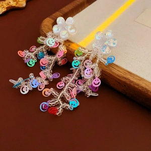 Détail macro de boucles d'oreilles fleuries avec paillettes smiley colorées