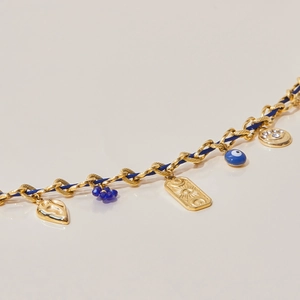 Detail of bohemian gold chain necklace with blue woven rope and evil eye charms