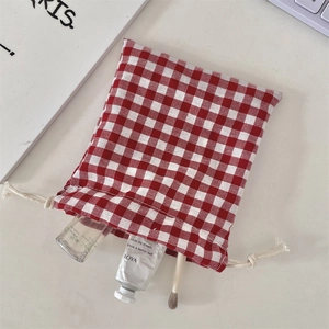 Close-up of red checkered drawstring storage bag with cosmetics and makeup brushes