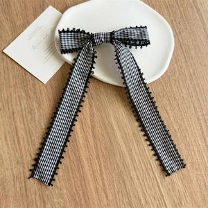 Détail d'une pince à cheveux nœud à carreaux noirs et blancs avec bordure en dentelle