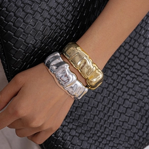 Detail of gold and silver metallic cuff bracelets featuring irregular hammered textures