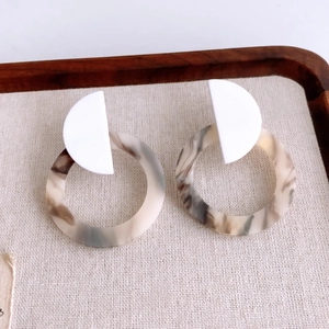 Detail of round hollow resin earrings with tortoiseshell texture and white studs
