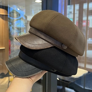 Close-up of brown and black knit beret hats featuring leather brims held in a store