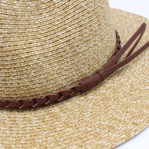 Gros plan sur la texture en paille tressée et la bande en cuir brun du chapeau Panama