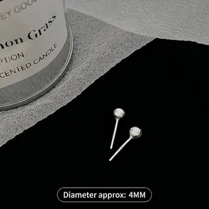 Macro detail of 4mm minimalist S925 sterling silver ball studs on black background