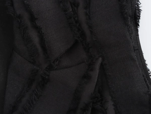 Gros plan sur le tissu noir texturé avec franges vintage et détails de matière tissée
