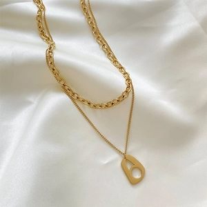 Détail du collier géométrique doré à double couche sur tissu satiné blanc