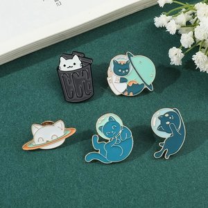 Close-up of five creative cartoon astronaut cat enamel pins with gold metal outlines