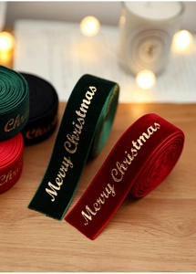 Detail of red and green velvet Christmas ribbons with gold foil Merry Christmas text