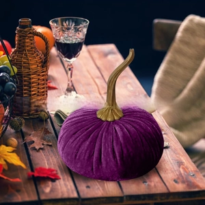 Close-up of purple velvet pumpkin decor with gold stem on a rustic autumn table