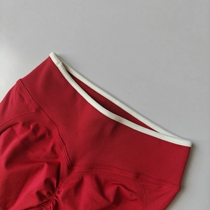 Detail of red high-waisted ribbed yoga leggings with scrunch butt and white trim edge