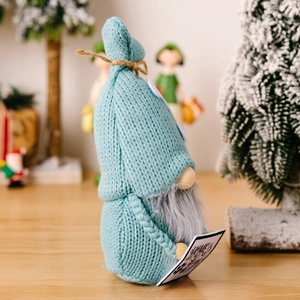 Detailed view of blue knitted Christmas gnome doll holding a wooden sign with home text