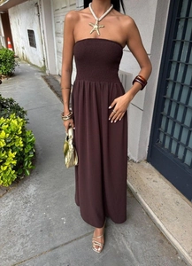 Close-up of strapless maxi dress featuring a ruched bodice and flowing brown fabric
