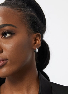 Close-up of minimalist silver hoop earrings worn by a model to show size and fit