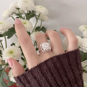 Detail of baroque pearl ring with silver intertwined lines on a model finger
