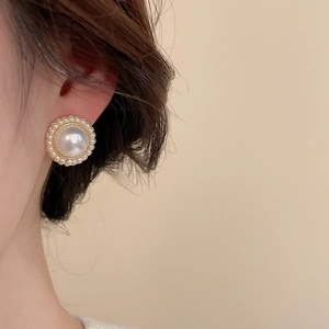 Detailed view of elegant pearl stud earrings with gold scalloped edges and tiny bead halo