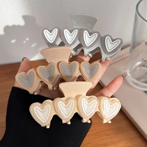 Three macaron heart hair claws in cream and grey shades held for display