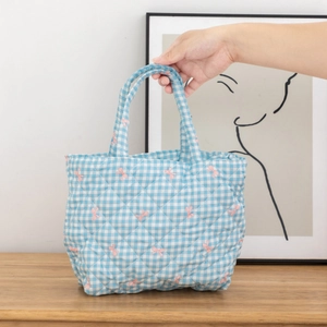 Detailed close-up of quilted floral tote bag with blue checks and pink bow patterns