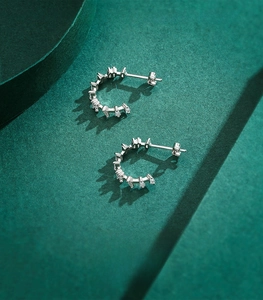 Detail of C-shaped 925 sterling silver hoop earrings with inlaid cubic zirconia stones