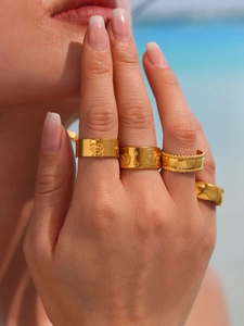 Close-up of gold chunky rings with skull, smiley face and star engravings on a model hand