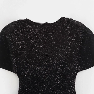 Elegante abito nero di paillettes con scollo all'americana e dettagli in tessuto lucido