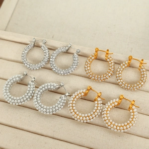 Créoles élégantes en or et argent avec strass et perles dans une boîte à bijoux