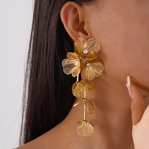 Close-up of golden floral tassel earrings featuring brushed metal and pavé diamond centers