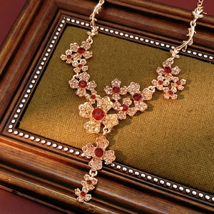 Close-up of rose gold vintage flower necklace with red and champagne crystals