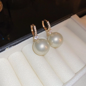 Macro shot of large white pearl hoop earrings with gold pavé crystal settings