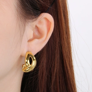 Close-up of 18k gold plated infinity symbol earrings worn on ear with polished finish