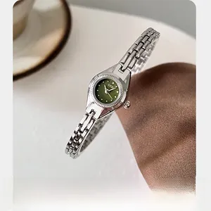 Détail de la petite montre GEDI argentée avec cadran vert olive sur tissu en soie brune