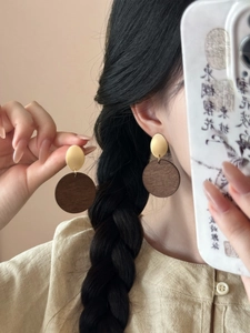 Detail of vintage geometric wood and gold metal drop earrings on a model's ear