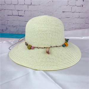 Detail of hand-woven straw sun hat featuring colorful beads and a floral pendant charm