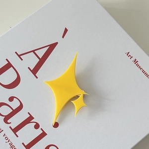 Gros plan détaillé d'une pince à cheveux étoile en acrylique jaune sur un livre d'art