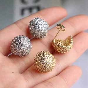 Close-up of geometric pavé sphere stud earrings in silver and gold finish with cubic zirconia
