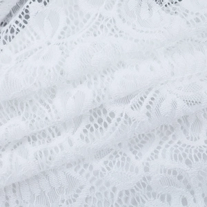Gros plan sur la dentelle florale blanche et le tissu en maille délicat du haut à manches