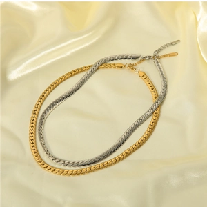 Flat lay of gold and silver snake bone necklaces with extension chains on silk fabric