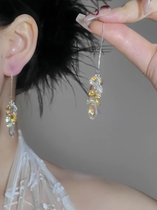 Detailed macro view of long silver tassel earrings featuring iridescent beads and teardrops