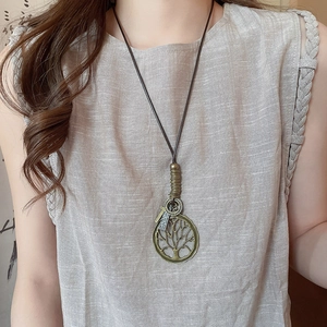 Detail of vintage bronze tree of life pendant on a long adjustable brown cord necklace