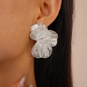 Macro detail of silver layered hollow flower earrings worn on the earlobe