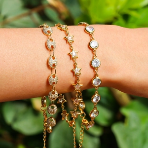Detail of three gold-plated bracelets with star and zircon charms on a model wrist